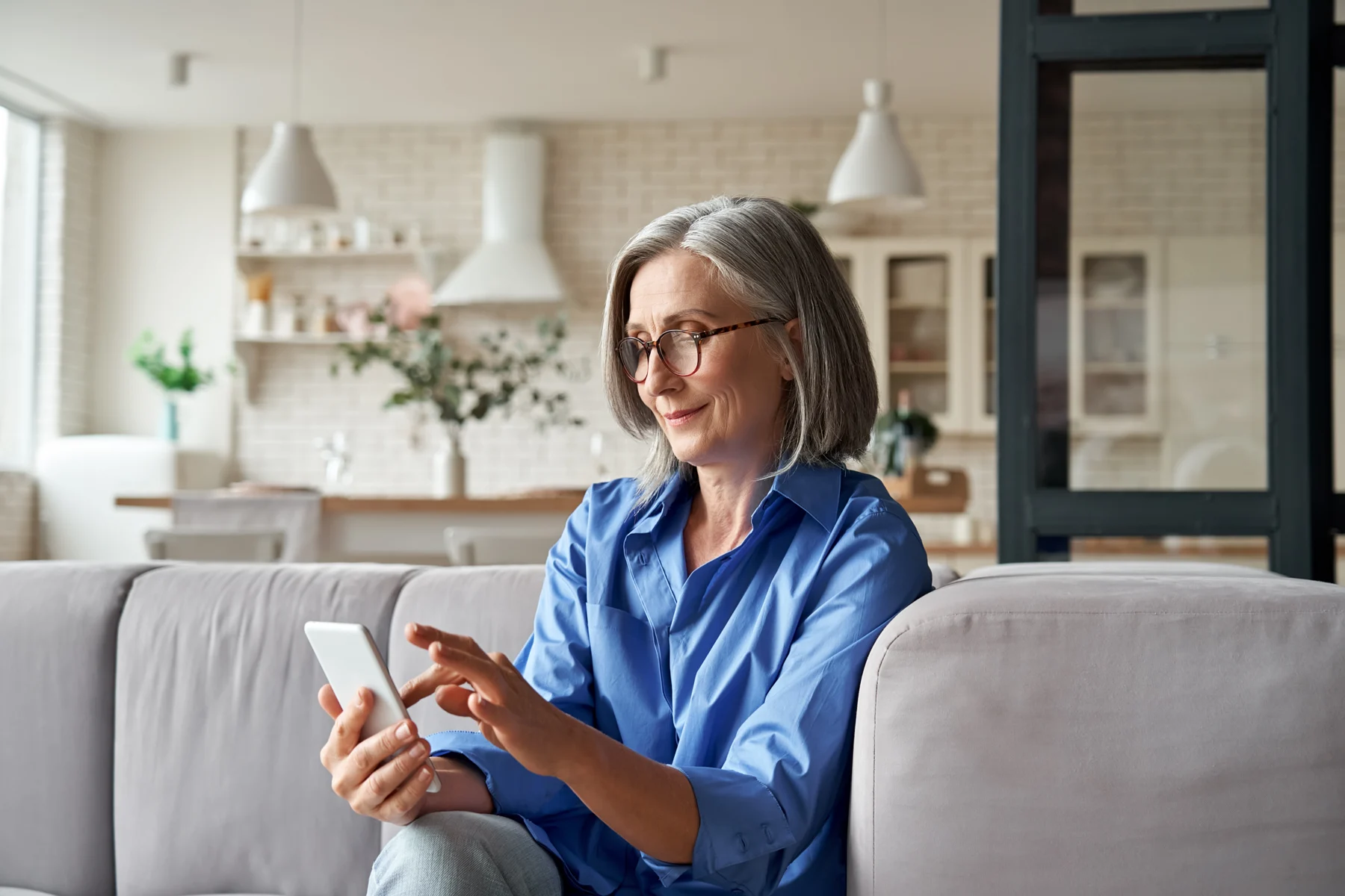 A woman sitting on a sofa and using her phone.