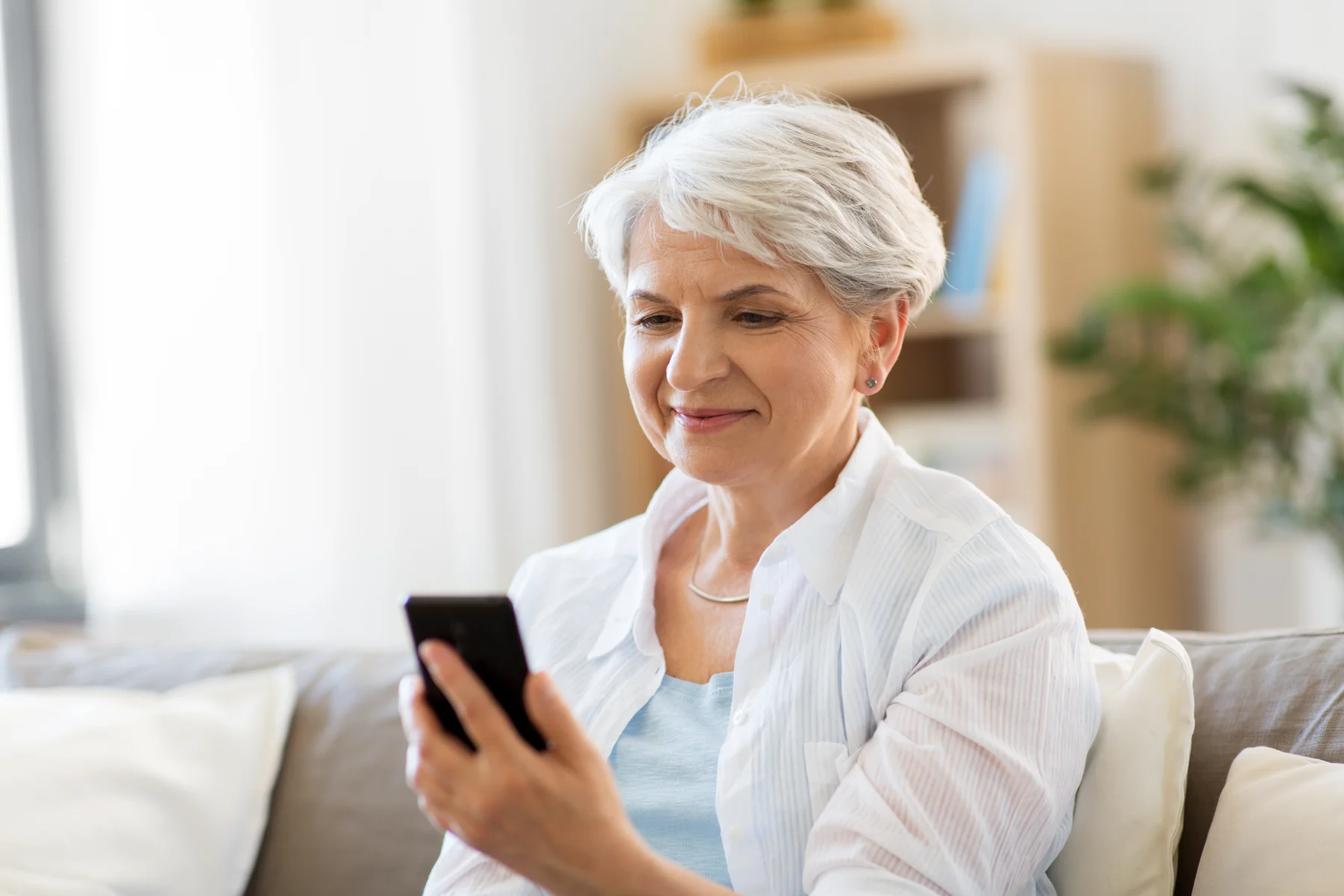 A woman using a phone in a bright room.