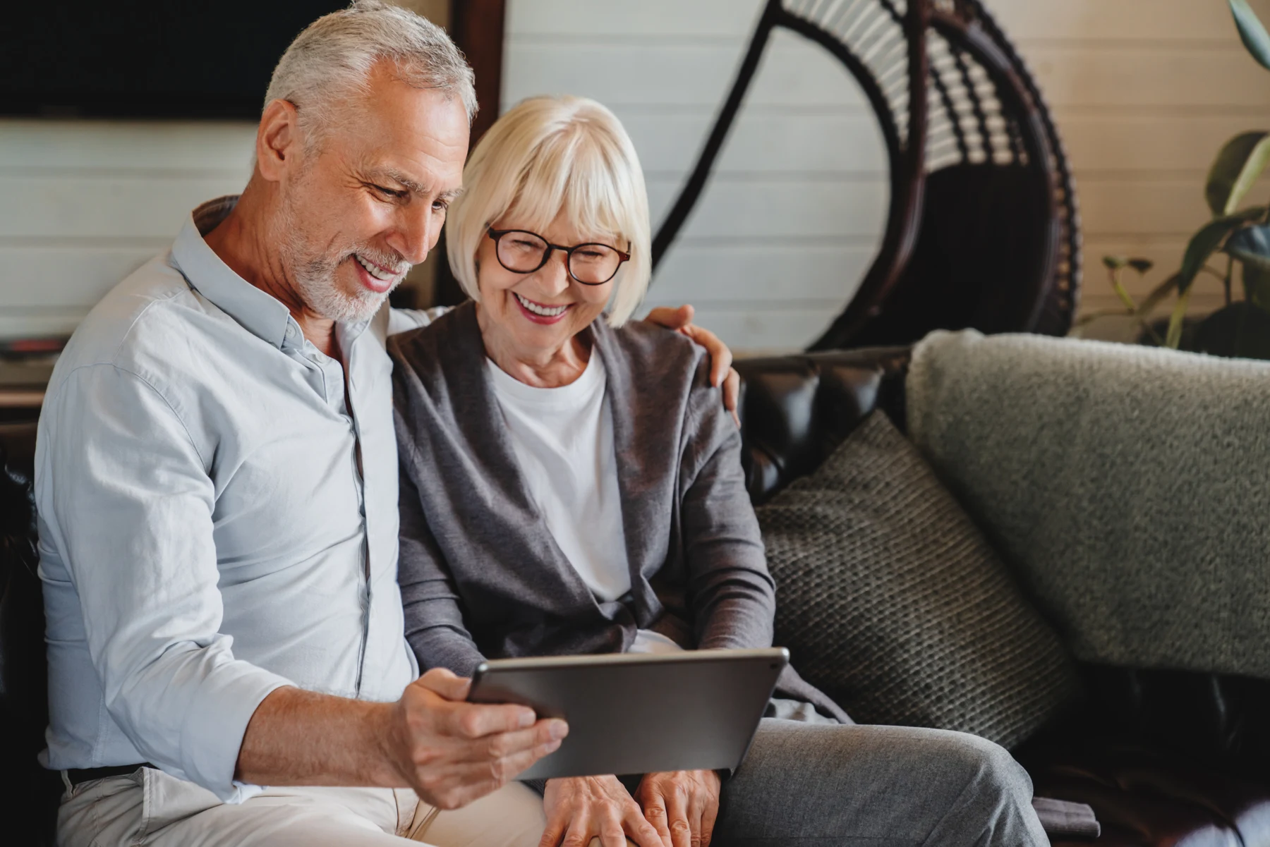 A couple sitting together at home and looking at a tablet.